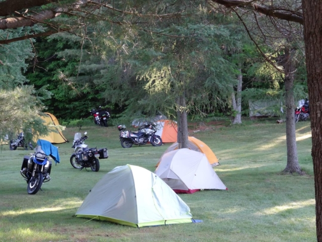 Several tents and motorcycles in a camp ground at dawn