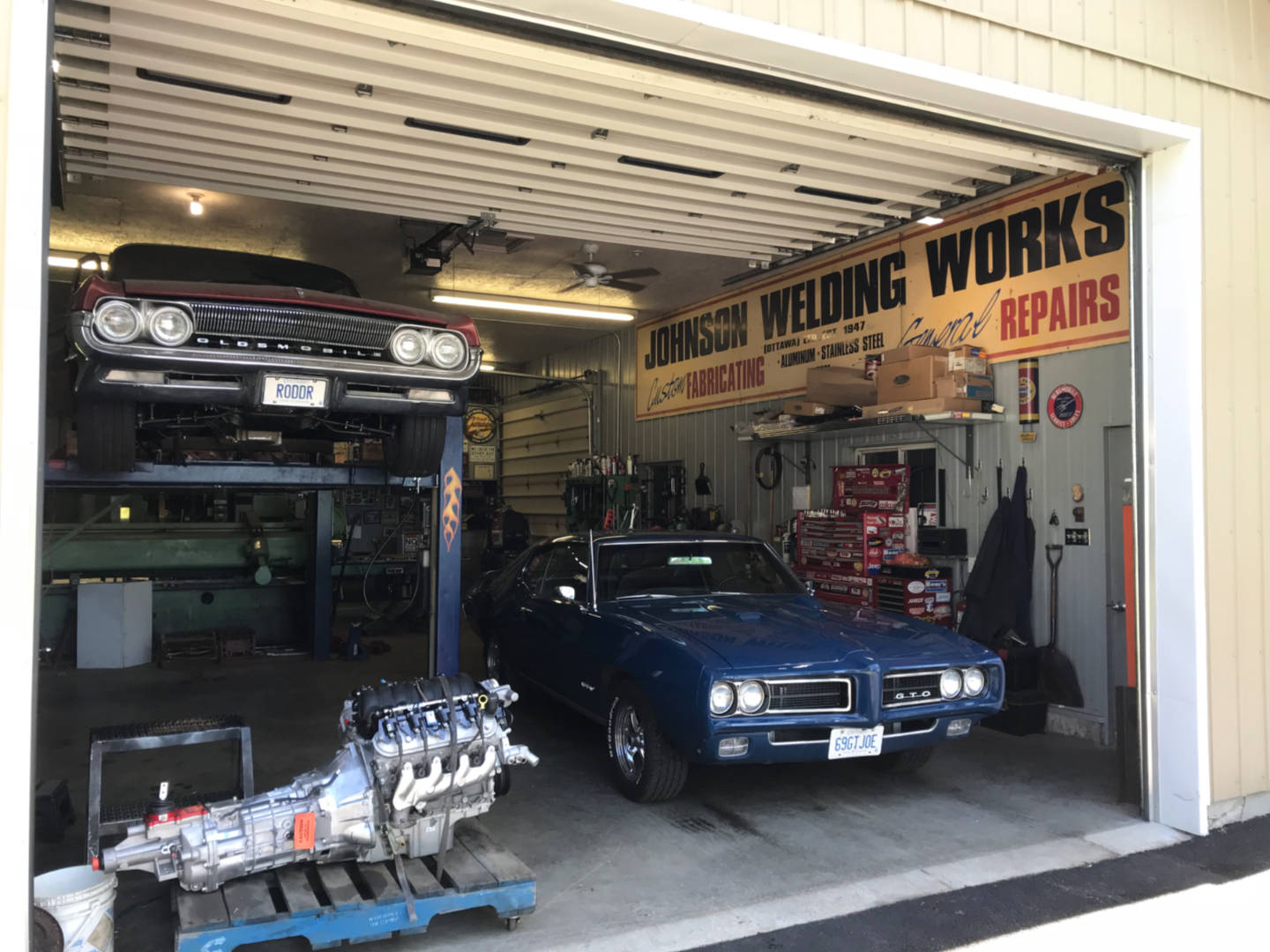 Photo of a blue Pontiac GTO in a garage awaiting repairs