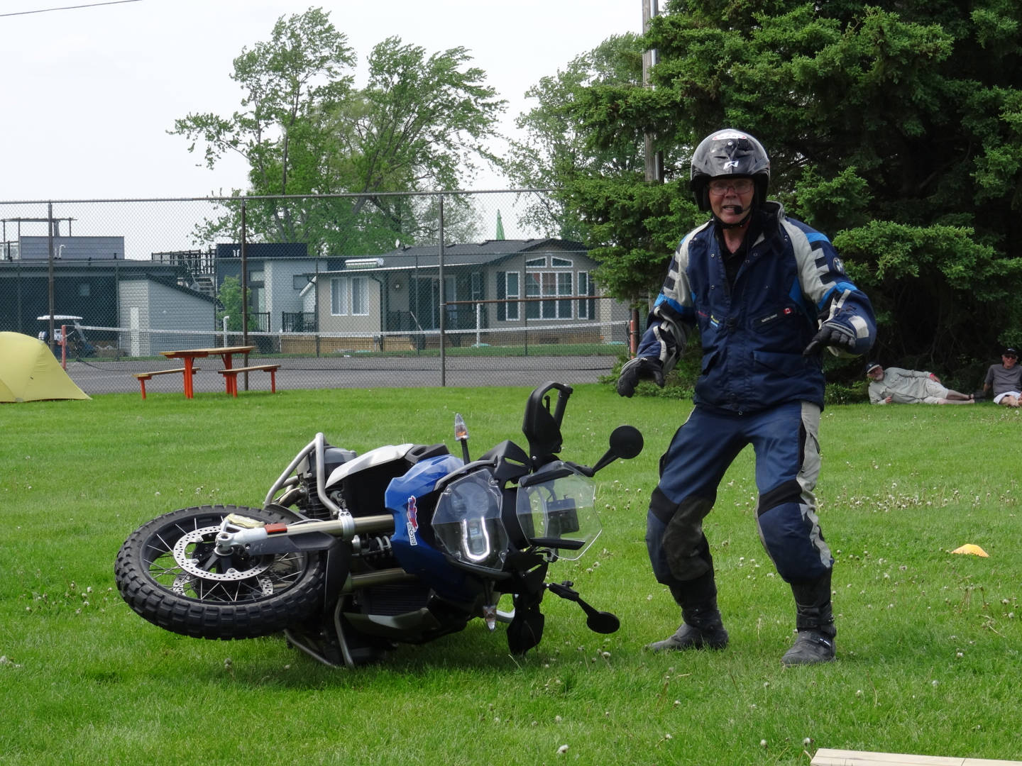A photo of a man standing beside a fallen motorcycle