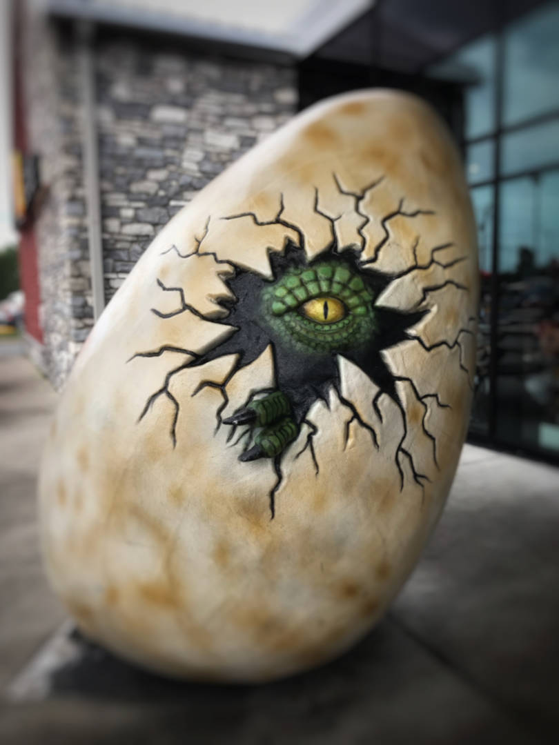 photo of a fiberglass dinosaur egg with a creature peering from within