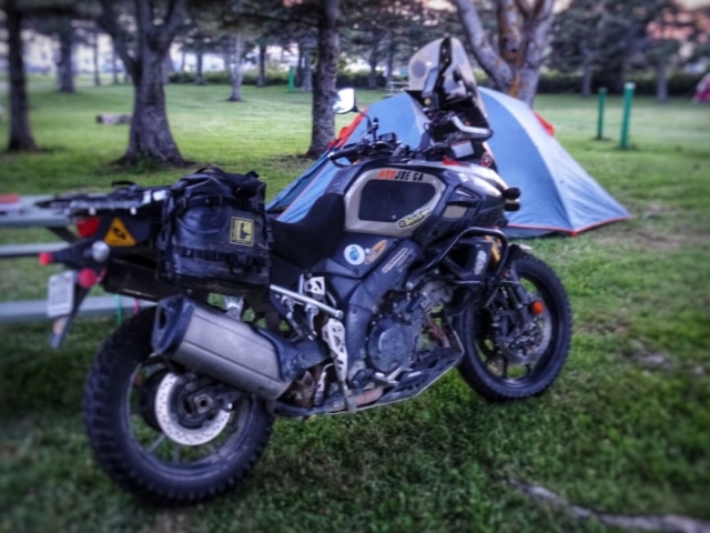 A Suzuki V-Strom parked in front of a blue tent at Linkletter Provincial Park