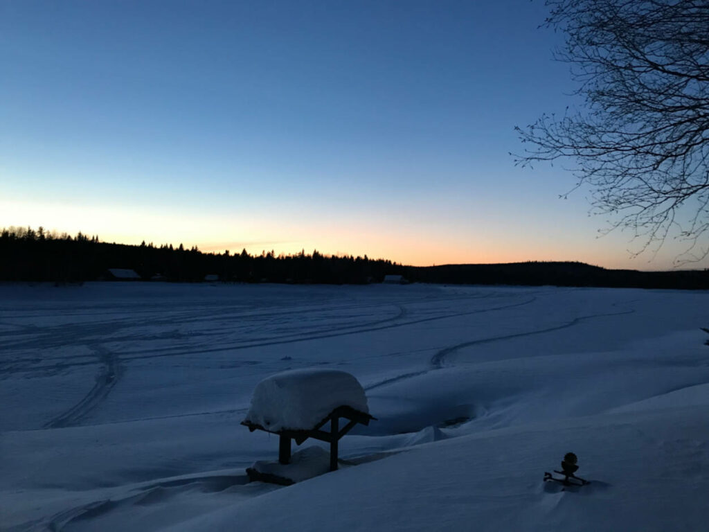 a photo of sunset in winter over a snow covered lake