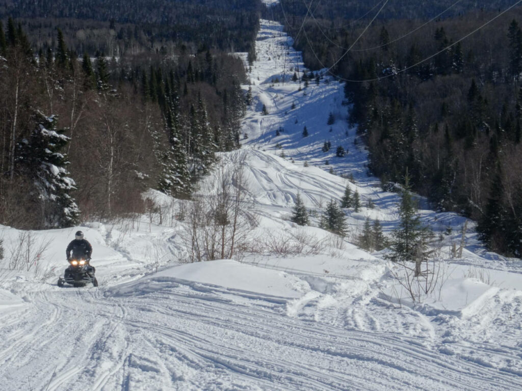 a photo of a snowmobile on a trail following a hydro line