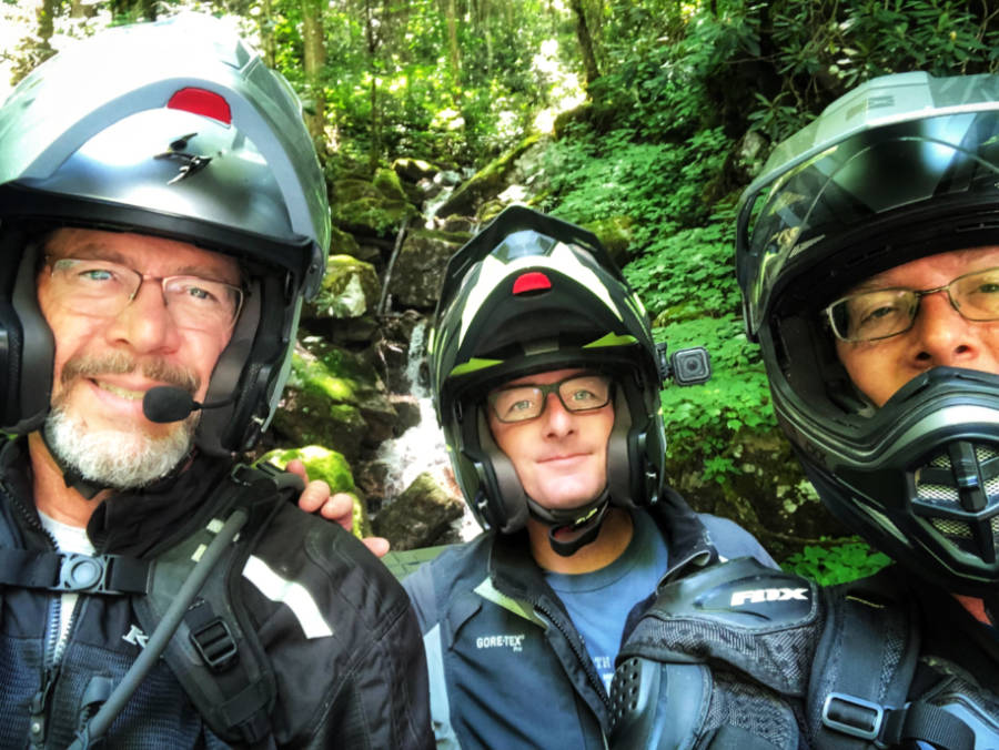 a photo of 3 motorcycle adventure riders in front of a waterfall on the MABDR