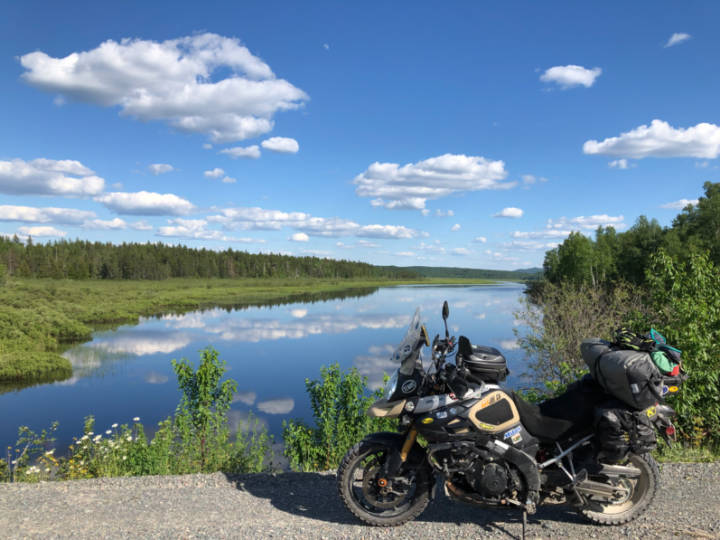 a photo of a motorcycle on a gravel road in front of a lake